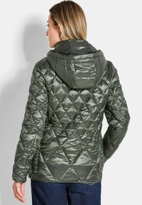 Gepolsterte gesteppte Jacke in Olivgrün, mit Kapuze, glänzender Textur, Rautenmuster und figurbetontem Design mit langen Ärmeln.
