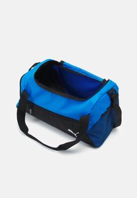 Sac de voyage bleu avec des accents noirs. Fabriqué en tissu durable, il dispose d'une fermeture éclair, de poignées de transport en sangle et de côtés en mesh pour la ventilation.