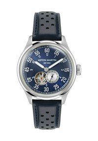 Un reloj de pulsera Aston Martin de cara azul con caja de plata, correa de cuero perforado, mecanismo de engranaje expuesto, grandes números blancos y dos agujas.