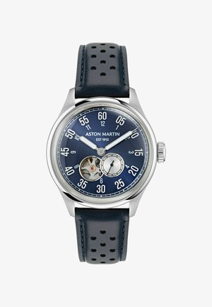 Náramkové hodinky Aston Martin s modrou tvárou, strieborným puzdrom, perforovaným koženým remienkom, odhaleným ozubeným mechanizmom, veľkými bielymi číslicami a dvoma ručičkami.
