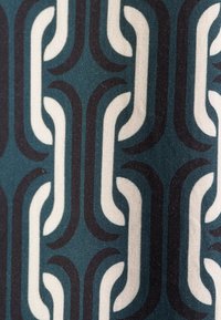 Tessuto astratto caratterizzato da un motivo a catena ripetuto nei toni del blu navy scuro, verde teal e bianco crema, con texture lisce e sottili variazioni di colore.