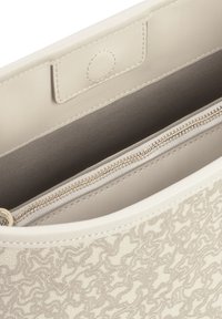 Bolso de mano de cuero beige claro con un patrón ondulado texturizado, que cuenta con un bolsillo interno con cremallera y un cierre a presión. Acabado suave y un brillo sutil.