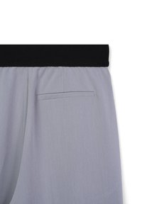 Pantalons gris clair avec une ceinture élastique noire et une seule poche horizontale à l'arrière du côté droit.