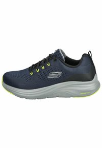 Marineblaue Mesh-Sportschuhe mit schwarzen und grauen Akzenten, ausgestattet mit gelben Ösen, einer gepolsterten grauen Sohle, die mit "VaporFoam" gekennzeichnet ist, und einem atmungsaktiven Design.