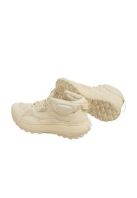 Beige high-top sneakers with a textured upper, padded collar, and sturdy rubber soles featuring pronounced treads for traction.