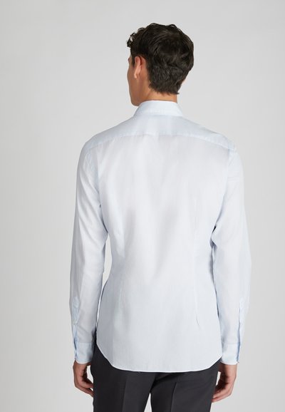 Camicia a maniche lunghe di colore azzurro chiaro, con colletto a punta e polsini con bottoni. Tessuto di cotone liscio con taglio classico e aperture laterali.