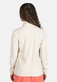 Vit långärmad jacka med hög krage, slät textur och figursydd design. Anmärkningsvärda sömdetaljer längs ärmarna och på baksidan.