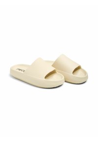 Des claquettes en caoutchouc beige avec un dessus texturé, un design ouvert à l'avant, et une semelle épaisse dotée d'une texture antidérapante.