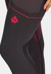 Czarne legginsy sportowe z teksturowanym wzorem, różowymi akcentami oraz różowym logo w okolicy uda. Wytrzymały, dopasowany krój.