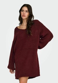 Bordowy, luźny sweter z dzianiny o szerokim dekolcie i długich rękawach, z prążkowaną fakturą i swobodnym krojem sięgającym ponad kolano.