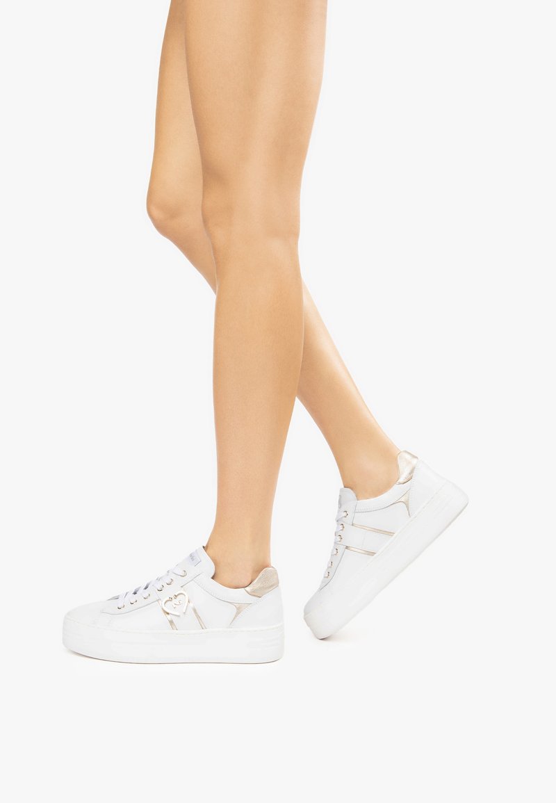 Sneakers bianchi con una finitura in pelle liscia, design con lacci, accenti metallici e una spessa suola piattaforma bianca. Caratterizzati da dettagli beige sottili.