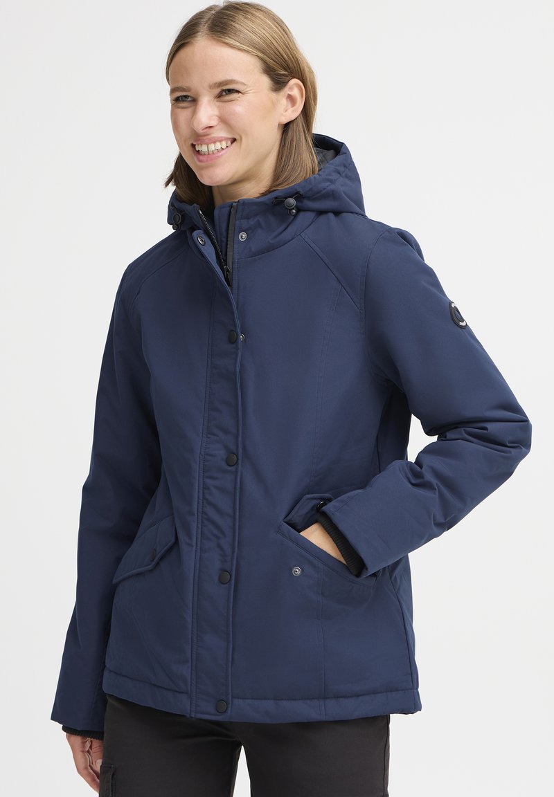 Veste isolée bleu marine avec capuche, boutons-pression, poches latérales et poignets côtelés. Tissu lisse avec une coupe décontractée.