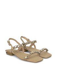 Sandali piatti beige con cinturini incrociati, decorati con pietre trasparenti e dorate; caratterizzati da una costruzione leggera e un tacco basso.