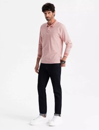 Vaaleanpunainen pitkähihainen poolopaita, jossa on kaulus ja kolme nappia, yhdistettynä tummiin farkkuihin ja valkoisiin tennareihin. Minimalistinen muotoilu, rento istuvuus.