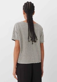 Chemise à manches courtes présentant un motif ondulé noir et blanc, en tissu léger, coupe décontractée et encolure ronde.