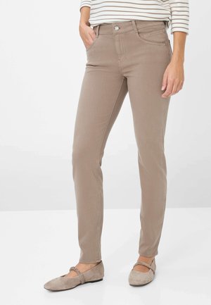 Hellbraune, schmal geschnittene Jeans mit vorderen Taschen, einem Knopfverschluss und glatter Textur. Getragen mit beigen Ballettschuhen und einem gestreiften Oberteil.