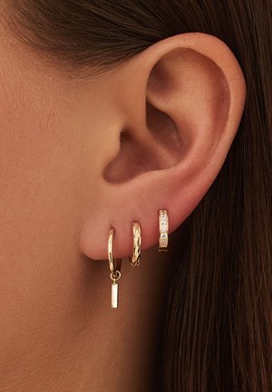 Trois boucles d'oreilles en or en différentes conceptions : l'une présente une finition lisse, une autre a un motif texturé et la dernière comprend de petites pierres claires.