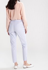 Ljusblå randiga byxor med slim fit, med bakfickor, tillsammans med en mjuk rosa långärmad skjorta och vita slip-on skor.