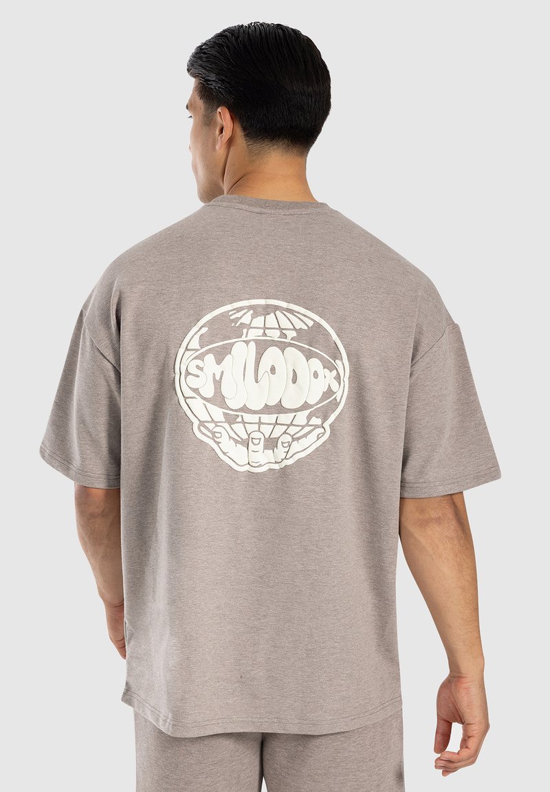 Grå bomulls t-shirt med korta ärmar, med en stor vit grafik av händer som håller en jordglob på ryggen. Avslappnad passform.