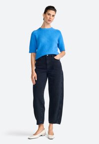 Lys blå kortærmet sweater, mørke højTaljede jeans og hvide sko med blokhæle. Blød tekstur med afslappet pasform og lige ben design.
