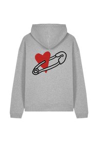 Šedá mikina s kapucí, která má na zádech černý obrys bezpečnostní spinky a vyšitý červený srdce. Měkký materiál a volný střih.