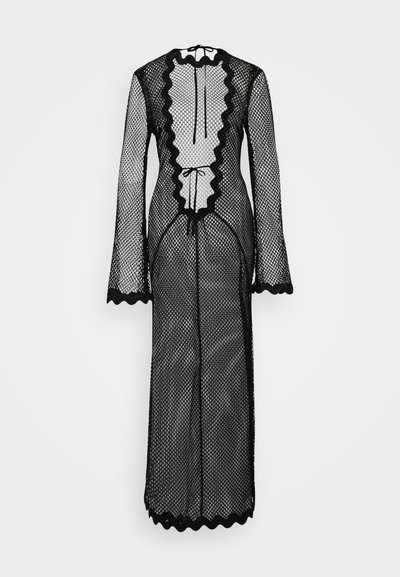 Juoda tinklinė suknelė ilgomis rankovėmis, su banguotais kraštais ir balta raukinėta juostele per visą priekį. Turi virvutės užsegimą kakle.