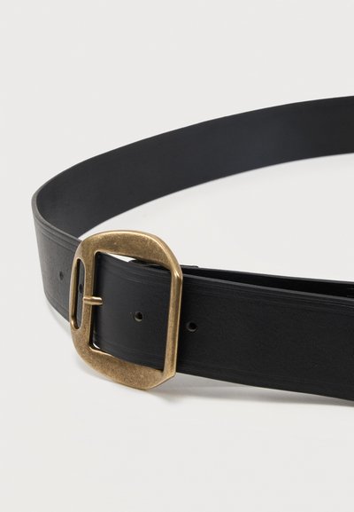 Μαύρη δερμάτινη ζώνη με οβάλ ορθογώνια πόρπη από παλαιωμένο ορείχαλκο, εμφανιζόμενη τυλιγμένη πάνω σε λευκή επιφάνεια.