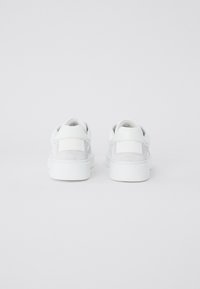Sneaker bianchi con una tomaia in pelle liscia e suede, punta rotonda e suola imbottita. Il tallone presenta un accento con etichetta del brand.