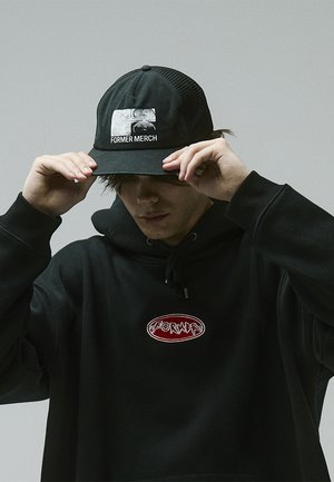 Black cap with "FORMER MERCH" printed in white, featuring a mesh back. Black hoodie with a circular embroidered logo. Textured fabric.