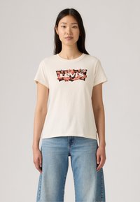T-shirt à manches courtes de couleur crème avec un design floral du logo Levi's dans des tons sombres et roses, fabriqué en tissu de coton doux.