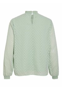 Light green blouse with long sleeves, featuring a textured chevron pattern, gathered neckline, and an open back with a small button closure.