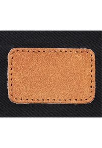 Patch rectangulaire en cuir marron avec couture marron foncé sur tissu noir, montrant une surface texturée et des coins arrondis.
