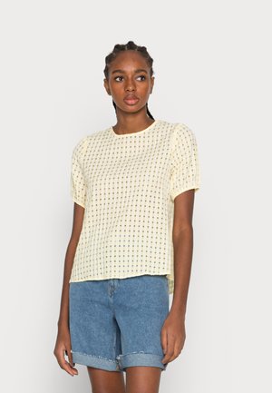 Top amarelo de manga curta com um padrão de grelha, corte descontraído, decote redondo e tecido texturizado. Combinado com calções de ganga azuis.