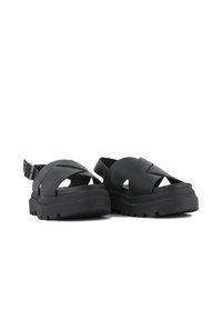 Zwarte rubberen sandalen met een kruisriemontwerp, verstelbare gesp, dikke gestructureerde zool en uitsparingen voor ademend vermogen.