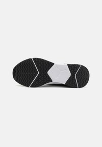 Semelle de chaussure de sport en noir et blanc avec un motif de semelle en zigzag, accent en mousse intermédiaire hexagonale et logo Puma en relief en blanc.