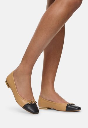 Tan and black leather ballet flats with a pointed toe, a gold accent at the front, and a small heel. Smooth texture throughout.