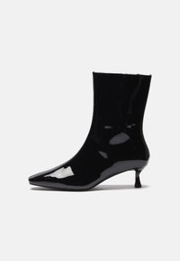 Sorte patent ankle boot med spiss tå, tettsittende form og en liten, slank hæl. Glatt tekstur og høyglanset finish.