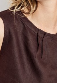 Top de lino marrón con cuello redondo y detalle de pliegue en el frente. Tejido ligero con una textura suave y un diseño limpio y simple.