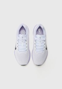 Nike idrettssko i hvit mesh med lilla aksenter. Har flate hvite lisser, svart logo og strukturert såle for bedre grep.