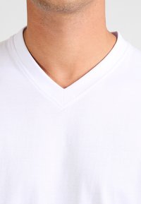 White cotton V-neck t-shirt with a smooth texture. The neckline features a clean, stitched finish, typical for casual wear.