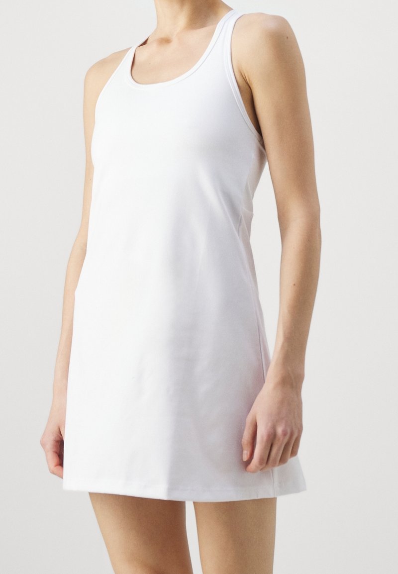 Robe blanche sans manches en tissu doux, avec un col rond et une coupe droite, tombant juste au-dessus du genou. Texture simple et lisse.