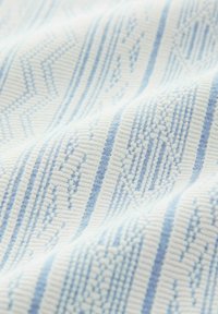 Soft white fabric with light blue geometric and striped woven patterns and textured ribbing.