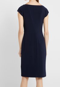 Vestido azul marino con mangas cortas, diseño ajustado y corte a la altura de la rodilla. Tela suave con una textura lisa y un sutil detalle de costura.