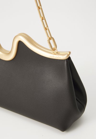 Black leather handbag with a wavy gold metal frame and chain strap. Features smooth texture and sculptural design details.