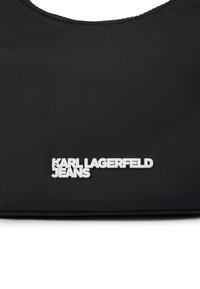 Fekete nylon táska sima textúrával, alján fehér "KARL LAGERFELD JEANS" logóval. Az alján kör alakú nyílással.