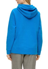 Blauwe hoodie met een grote kap, gemaakt van zachte stof. Beschikt over een buidelzak en ribbels aan de manchetten. Gepaarde met geprinte broek.