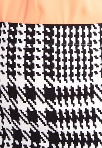 Svart och vit tyg med ett hundtandsmönster, med en slät textur. Den övre delen är i en enhetlig persikofärg, sydd längs sömmen.