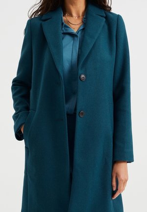 Abrigo de mezcla de lana en color verde azulado con un diseño entallado, solapas de muesca, dos botones y bolsillos laterales, que presenta una textura suave y una forma estructurada.