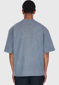 Graues Baumwoll-T-Shirt mit kurzen Ärmeln, lockerer Passform und Rundhalsausschnitt. Hat eine glatte Textur und dezente Nähte.