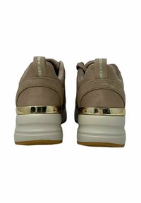 Zapatillas de ante en beige con un tacón elevado, que presentan un acento dorado en la parte trasera, una suela blanca texturizada y cordones planos.